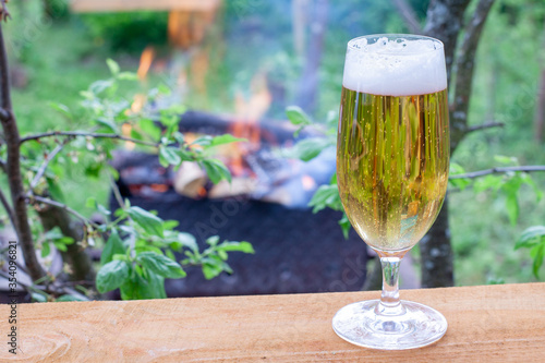 glass glass with cold beer on a warm evening in nature. beer on the background of a burning fire in the grill