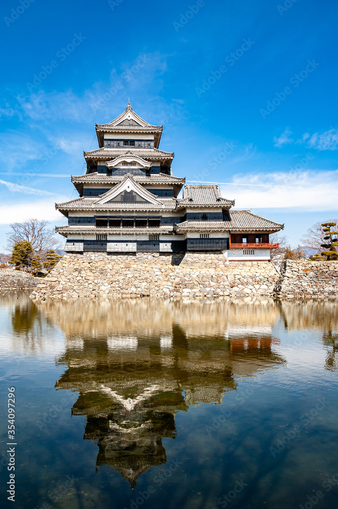 Matsumoto Castle built in 16th Century in Matsumoto City, Nagano, Japan with a reflection on the pond during a winter sunny day