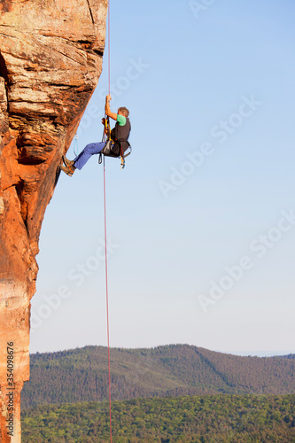 Rock climber and photographer Norbert Frank rappeling from a sandstone rock