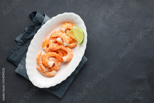 Seafood. Boiled shrimp in a plate on a black background. Top view with copy space.