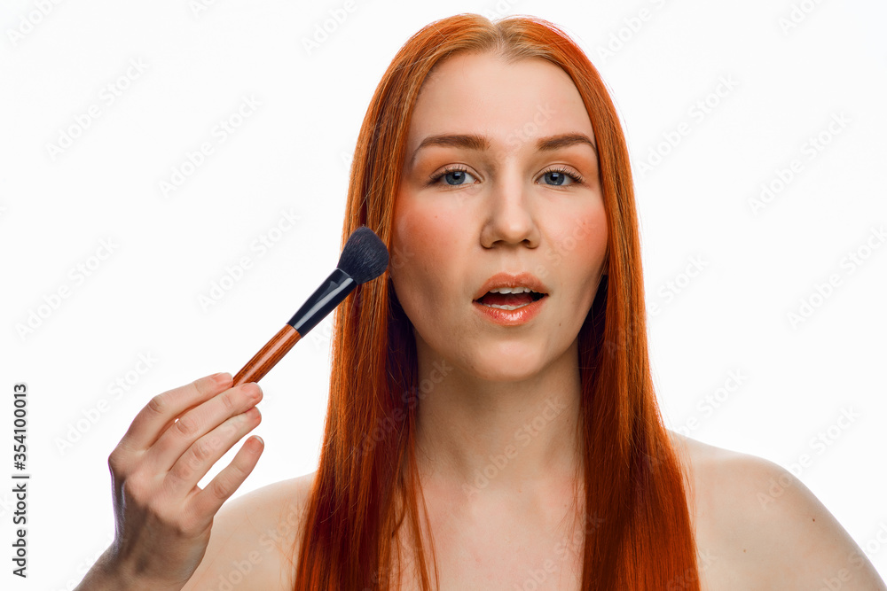 close beauty portrait of a red-haired girl with a brush for applying makeup. Isolated on a white background. close beauty portrait of a red-haired girl with a brush for applying makeup. Isolated on a white background.