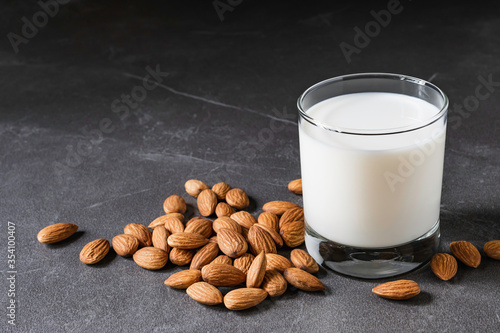 Close up glass of milk with almonds nut on table.