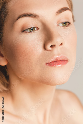 Closeup portrait of a beautiful girl with green eyes, nude make-up, perfect skin, studio shot. The concept of natural beauty.