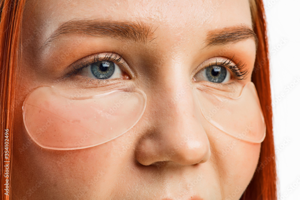 Fototapeta premium close beauty portrait of a red-haired girl with clean skin and patches under her eyes. Isolated on a white background.