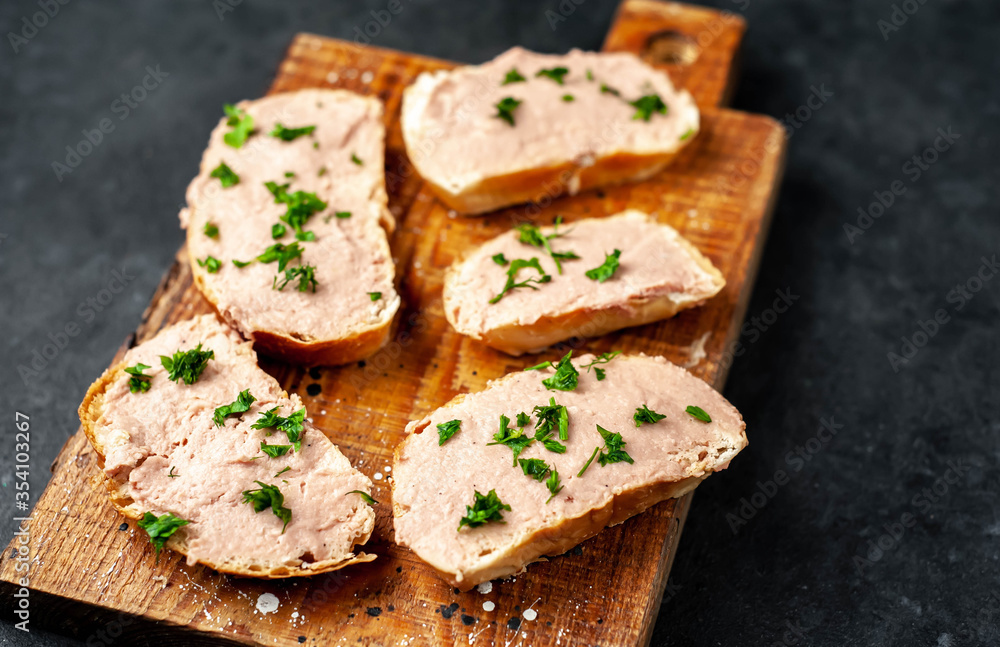 
Chicken pate on toast with fresh parsley on a cutting board on a stone background