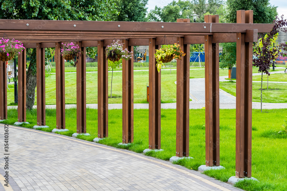 flowers in tubs hanging on an arch in landscape design, a path for a walk in the park paved with stone tiles