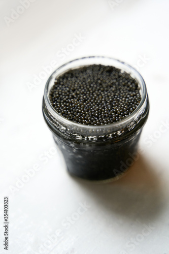 black caviar in a glass jar on a white background