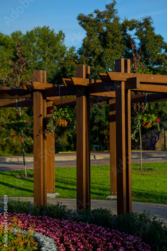 Walking path paved with stone tiles under a wooden arch in the garden flowerbed with flowers landscape design of the territory