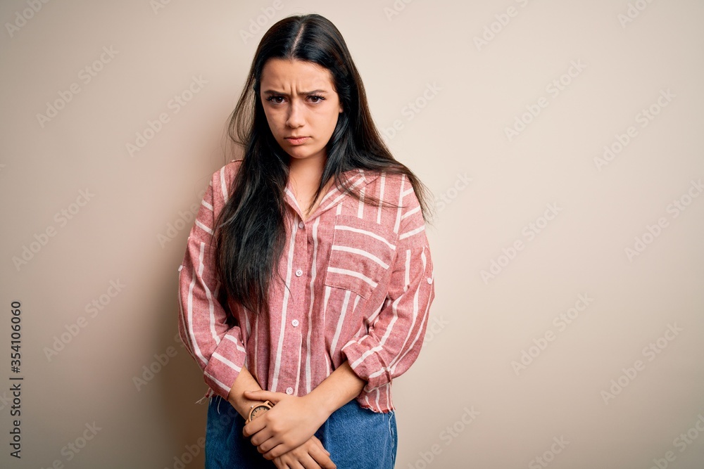 Young brunette woman wearing casual striped shirt over isolated background skeptic and nervous, frowning upset because of problem. Negative person. Young brunette woman wearing casual striped shirt over isolated background skeptic and nervous, frowning upset because of problem. Negative person.