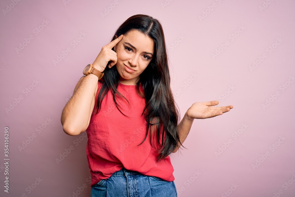 Young brunette woman wearing casual summer shirt over pink isolated background confused and annoyed with open palm showing copy space and pointing finger to forehead. Think about it. Young brunette woman wearing casual summer shirt over pink isolated background confused and annoyed with open palm showing copy space and pointing finger to forehead. Think about it.