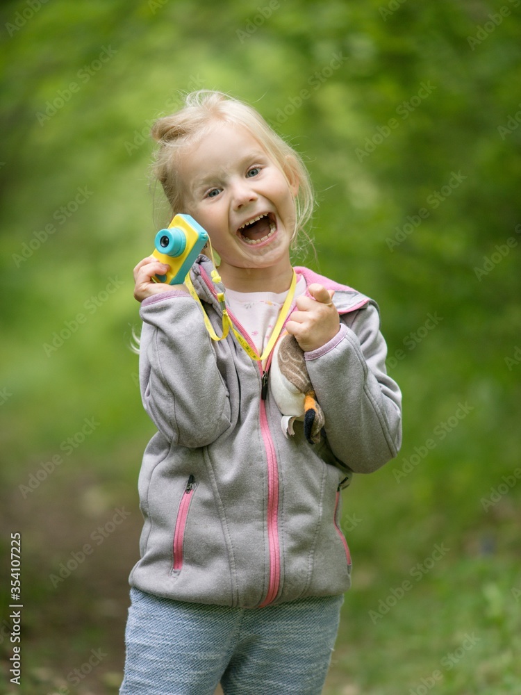Little happy girl with a camera in the park at the end of the quarantine. Little happy girl with a camera in the park at the end of the quarantine.