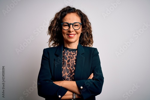 Photographie Middle age brunette business woman wearing glasses standing over isolated white background happy face smiling with crossed arms looking at the camera