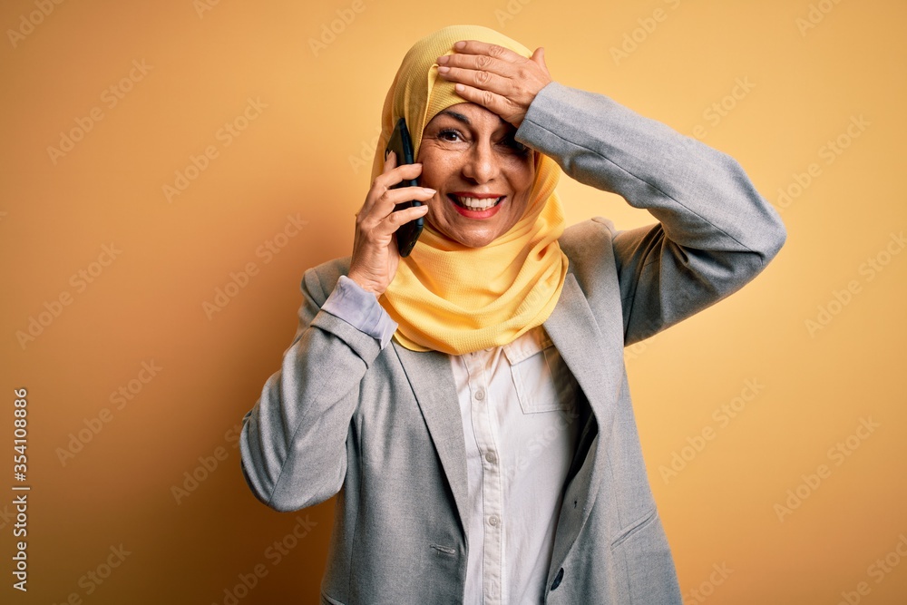 Middle age woman wearing traditional muslim hijab having conversation talking on smartphone stressed with hand on head, shocked with shame and surprise face, angry and frustrated. Fear and upset Middle age woman wearing traditional muslim hijab having conversation talking on smartphone stressed with hand on head, shocked with shame and surprise face, angry and frustrated. Fear and upset