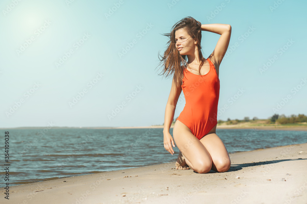 Young attractive brunette woman in red body enjoying the summer  with sea on background