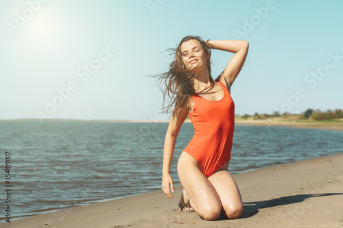 Young attractive brunette woman in red body enjoying the summer  with sea on background