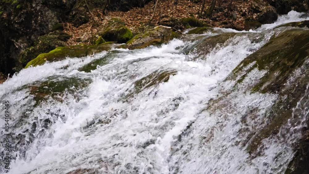 Stream water from waterfall flowing on large stones in mountain river. Flow mountain river in waterfall cascade. Stream water from waterfall flowing on large stones in mountain river. Flow mountain river in waterfall cascade.