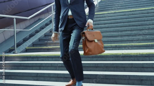 A young man in a business suit runs down stairs to the underground with a suitcase in his hand. Slow motion. Business on the go. Business concept. Prores 422.