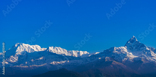 Beautiful sunrise view of mountain range with snowy peaks. Annapurna range in Himalayas. Machchapuchchre/ Fishtail, Annapurna and Himchuli Peaks, view from Sarangkot, Pokhara, Nepal. © Dzianis Rakhuba