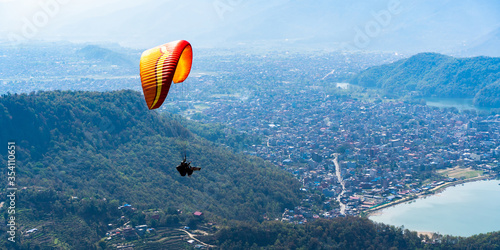 Paragliding in Nepal. Paraglider on the background of Phewa Lake, Pokhara city and surrounding villages. Stock photo.