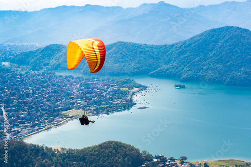 Paragliding in Nepal. Paraglider on the background of Phewa Lake, Pokhara city and surrounding villages. Stock photo.