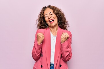 Middle age beautiful businesswoman wearing jacket standing over isolated pink background celebrating surprised and amazed for success with arms raised and eyes closed