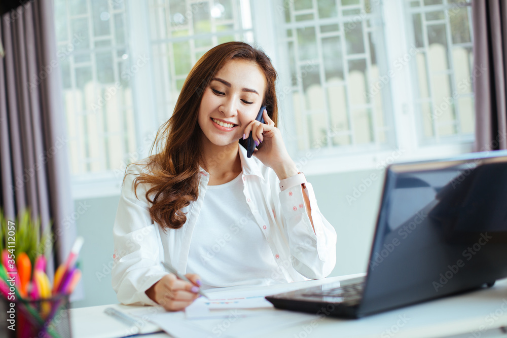 happy young cheerful business woman at home office working on smartphone and laptop happy young cheerful business woman at home office working on smartphone and laptop