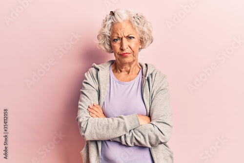 Senior grey-haired woman wearing casual sporty clothes skeptic and nervous, disapproving expression on face with crossed arms. negative person.
