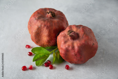 Dried ugly pomegranates with seeds and leaves on a gray background. Close up.