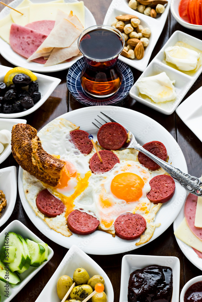 Traditional Turkish Spreading Breakfast on the wooden table.Egg with sausage in the round white plate in front of breakfast table.Vertical image.