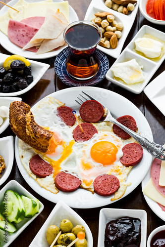 Traditional Turkish Spreading Breakfast on the wooden table.Egg with sausage in the round white plate in front of breakfast table.Vertical image.