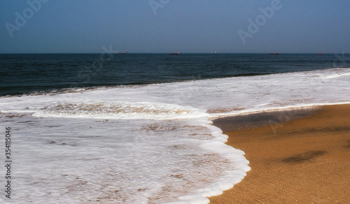 blue sky, yellow sand, beach and the white foam of waves, India