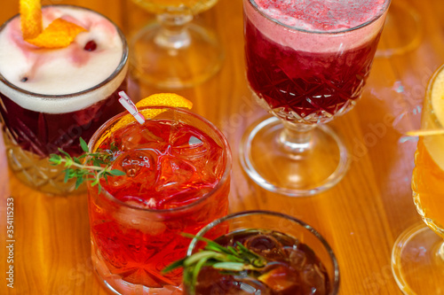 Set of alcoholic multicolor cocktails with fruits on the wooden table.