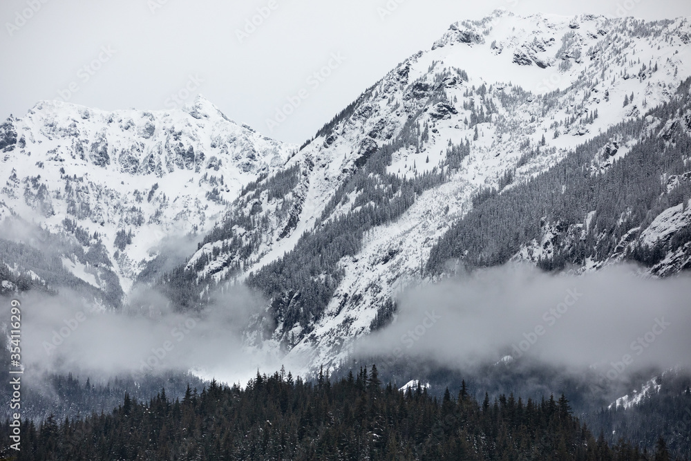 Mountain landscape of snow covered peaks and low valley clouds