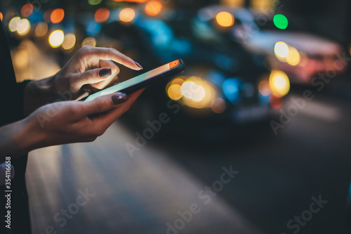 Female hands pointing on screen smartphone background headlights auto cars, tourist hipster waiting using mobile phone, traveler connect wifi internet and calls taxi