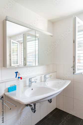 clean and bright modern bathroom with cleaning supplies on the sink