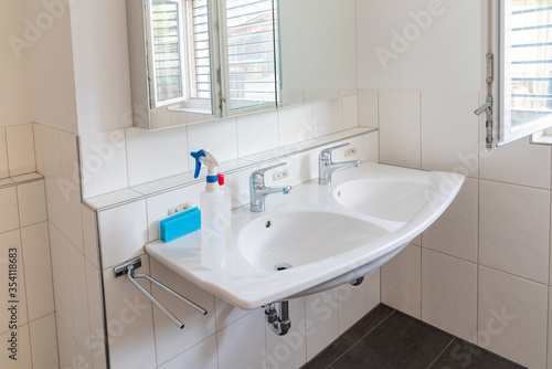clean and bright modern bathroom with cleaning supplies on the sink