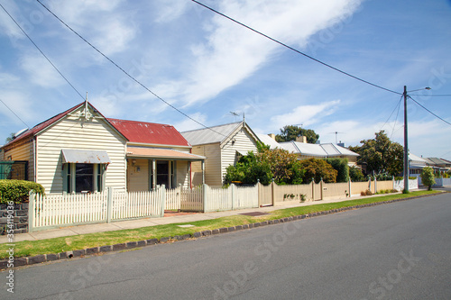 Fototapeta Naklejka Na Ścianę i Meble -  Traditionally built row of bungalow cottages in the 20th century Australian style with painted picket fences. Some of the houses require painting.