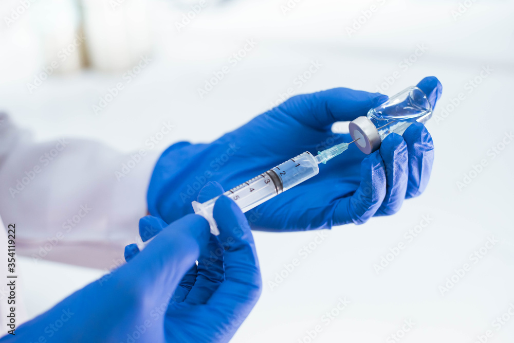 Doctor in blue glove filling syringe with vaccine Doctor in blue glove filling syringe with vaccine