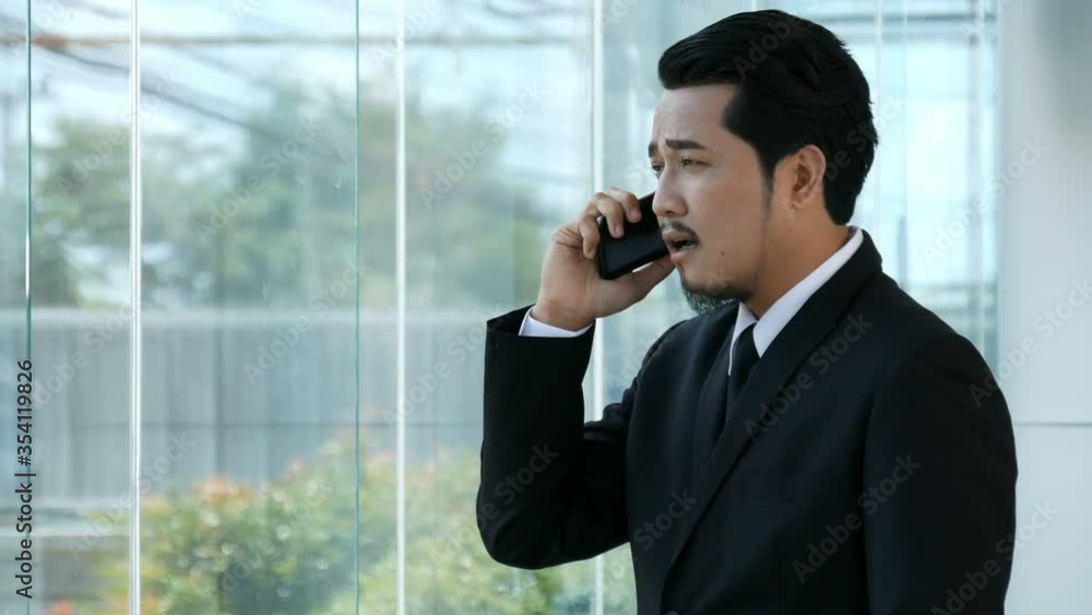 depressed young business man is talking on smartphone in office. 4k video