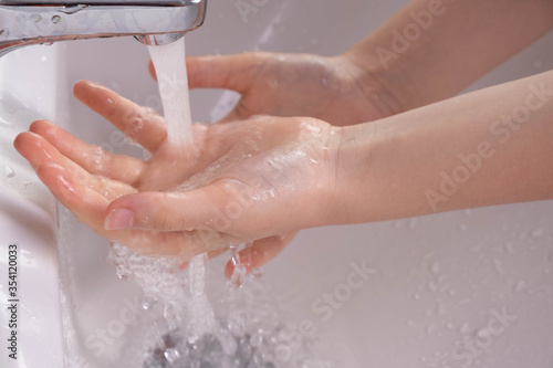 girl washes her hands under the pressure of water from the tap