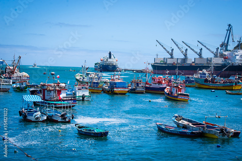a daily view of the city center of San Antonio, in Chile in a summer day. People walking by seaside promenade in the sunny day next to the sea. Everywhere is full of colors and good vibes.  
