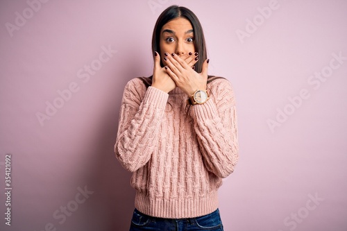 Young beautiful brunette woman wearing casual sweater over isolated pink background shocked covering mouth with hands for mistake. Secret concept.