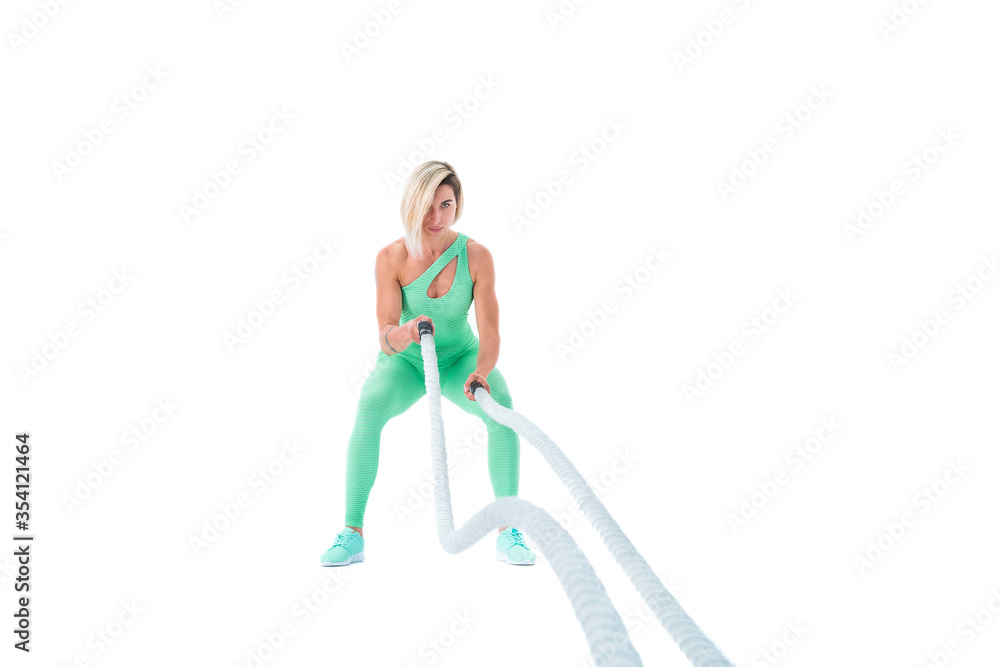 Woman doing exercises with battle rope. Photo of muscular model in military sportswear isolated on white background. Strength and motivation Woman doing exercises with battle rope. Photo of muscular model in military sportswear isolated on white background. Strength and motivation