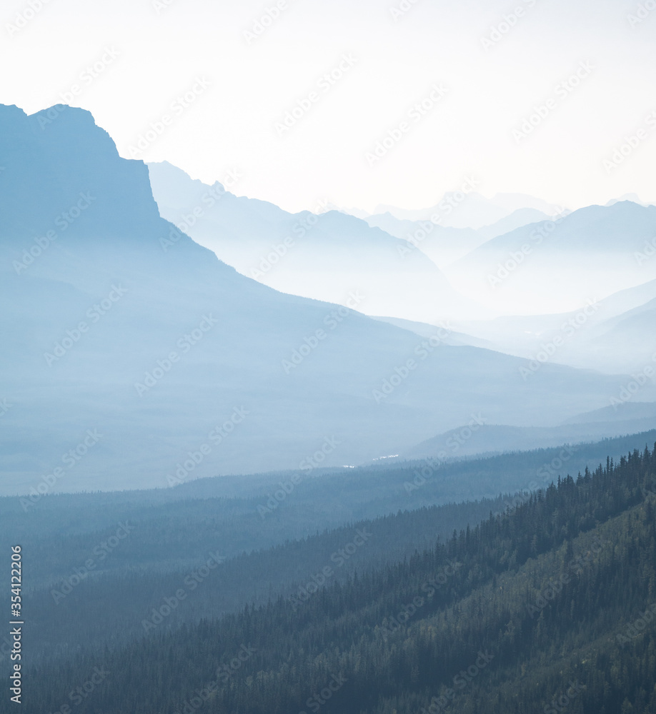 Hazy valley with mountains silhouettes, shot at Mount St. Piran summit, Banff National Park, Alberta, Canada