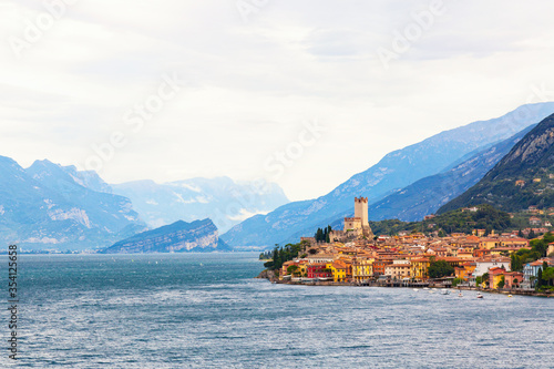 Ancient tower and fortress in old town Malcesine at Garda Lake. Mountains with clody sky in the background. Italian landscape. Small town Malcesine near Monte Baldo mountain, Italy.