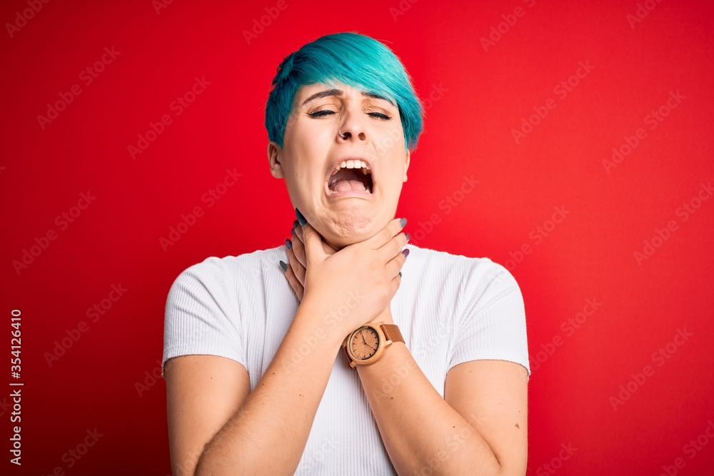 Young beautiful woman with blue fashion hair wearing casual t-shirt over red background shouting suffocate because painful strangle. Health problem. Asphyxiate and suicide concept.