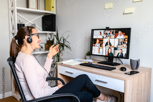 Young successful employee is have a meeting with her team using a headset, she is sitting relaxed and smiling, a middle side shot. photo