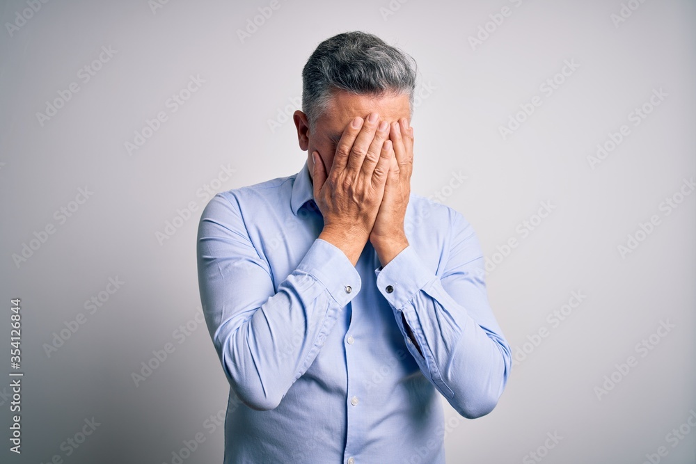 Middle age handsome grey-haired business man wearing elegant shirt over white background with sad expression covering face with hands while crying. Depression concept. Middle age handsome grey-haired business man wearing elegant shirt over white background with sad expression covering face with hands while crying. Depression concept.