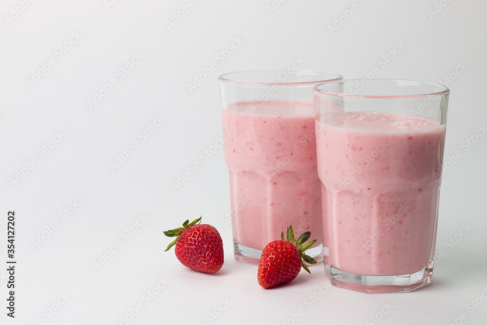 A glass of fresh strawberry smoothie on a white background. Summer drink shake, milkshake and refreshment organic concept. A glass of fresh strawberry smoothie on a white background. Summer drink shake, milkshake and refreshment organic concept.