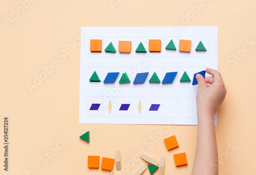 The child arranges blocks of various shapes according to the pattern. The development of thinking, attention, quick wit, imagination photo